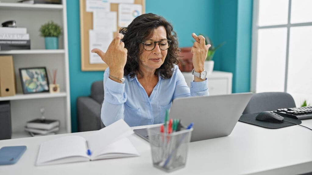 a woman crossing her fingers at her computer